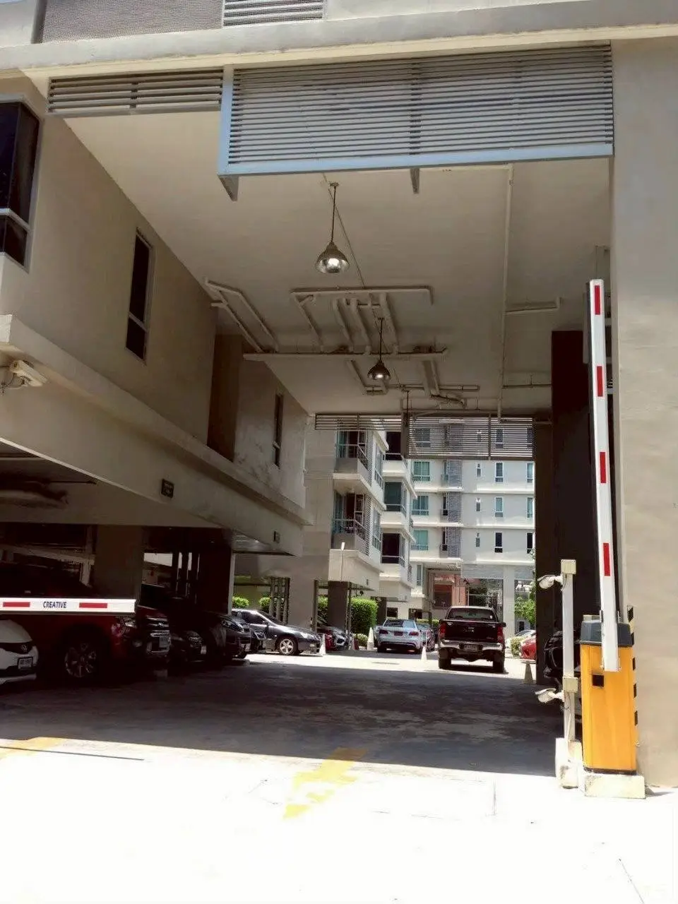 Modern apartment building entrance with parking area and security gate.