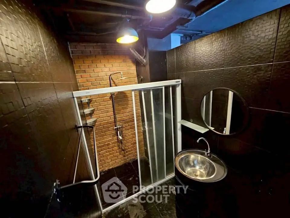 Stylish industrial bathroom with brick wall and modern fixtures