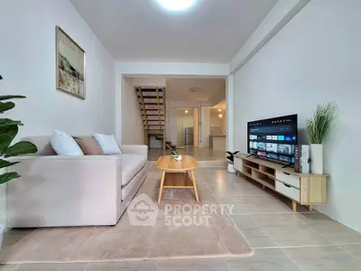 Modern living room with stylish furniture and open layout, featuring a cozy sofa and sleek TV setup.