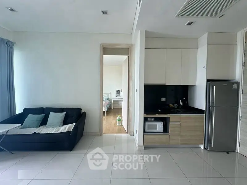 Modern open-plan living room with sleek kitchen and cozy seating area, perfect for urban living.