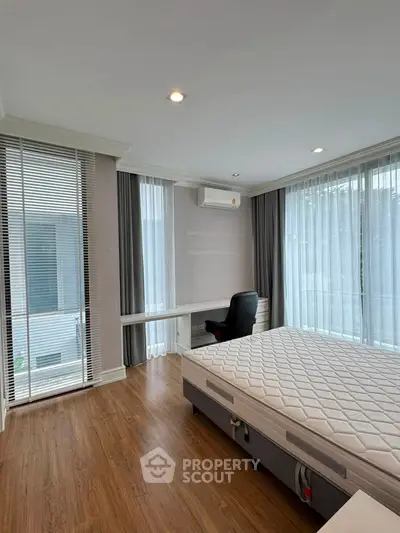 Spacious bedroom with large windows and modern furnishings in a stylish apartment.