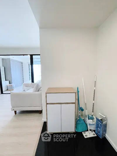 Modern living room with sleek furniture and cleaning supplies in a bright, open space.
