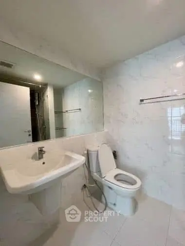 Modern bathroom with sleek white fixtures and large mirror in a contemporary home.