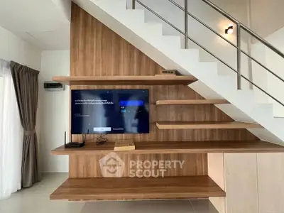Modern interior with stylish wooden shelving under staircase and mounted TV