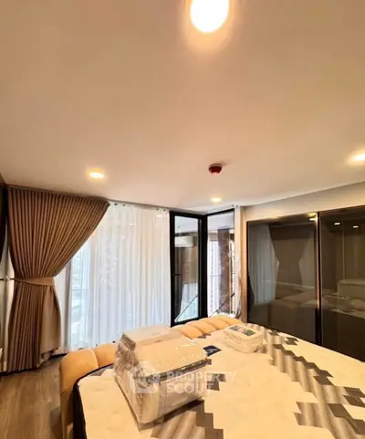 Spacious bedroom with large windows and modern decor in a luxury apartment.