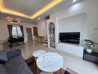 Modern living room with stylish decor and open dining area, featuring sleek furniture and ambient lighting.