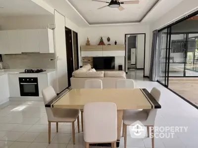 Modern open-plan living room with kitchen, featuring sleek design and large sliding glass doors.