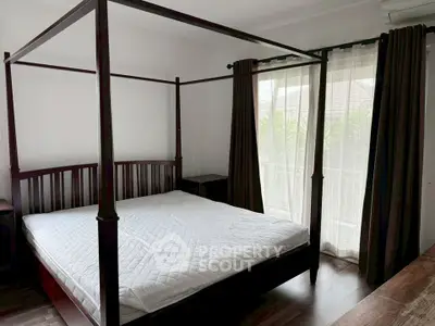 Spacious bedroom with elegant four-poster bed and large windows for natural light.