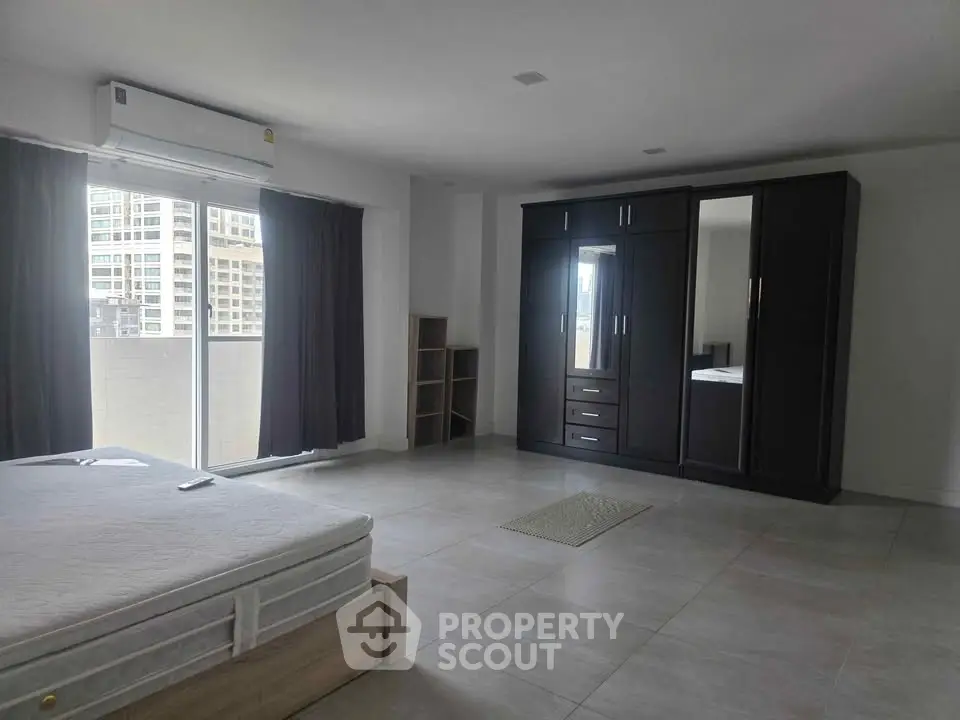 Spacious bedroom with large wardrobe and balcony access in modern apartment.