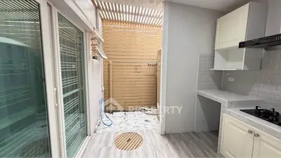 Modern kitchen with open layout and gas stove, featuring sleek cabinetry and sliding glass doors.