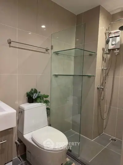 Modern bathroom with glass shower and sleek fixtures in contemporary apartment.