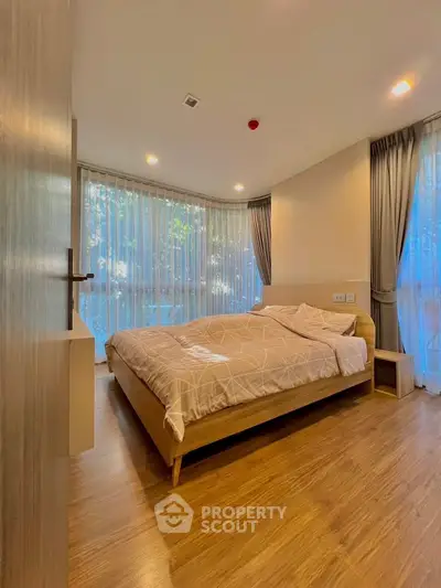 Spacious bedroom with large windows and wooden flooring