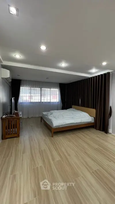 Spacious bedroom with modern decor and large windows for natural light.