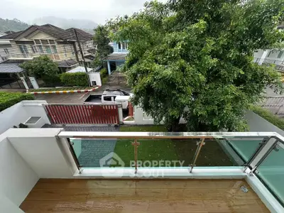 Charming balcony view overlooking lush greenery and residential street, perfect for relaxation.