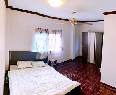 Spacious bedroom with modern decor and ceiling fan, featuring a large wardrobe and stylish tiled flooring.