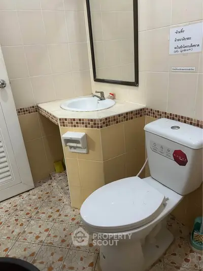 Compact bathroom with tiled floor, sink, and toilet in a cozy real estate property.
