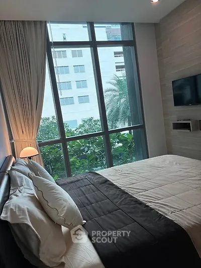 Luxurious bedroom with floor-to-ceiling windows and modern decor, offering a serene garden view.