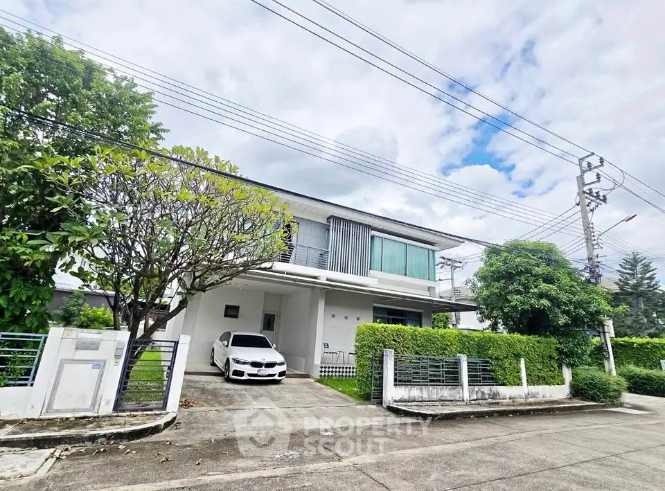 Modern two-story house with driveway and lush greenery in a serene neighborhood.