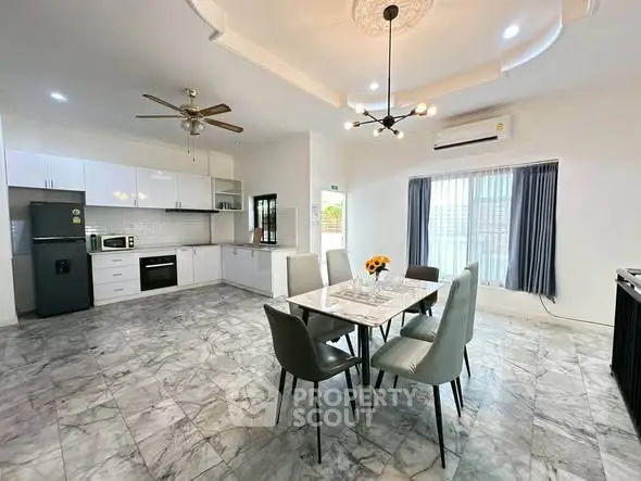 Spacious modern kitchen with dining area, featuring marble flooring and elegant lighting.