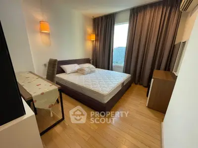 Cozy bedroom with wooden flooring and modern furnishings in a high-rise apartment.