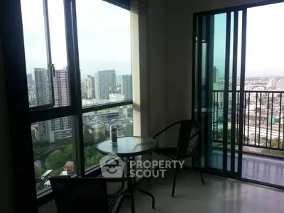 Stunning high-rise balcony with panoramic city views and cozy seating area.