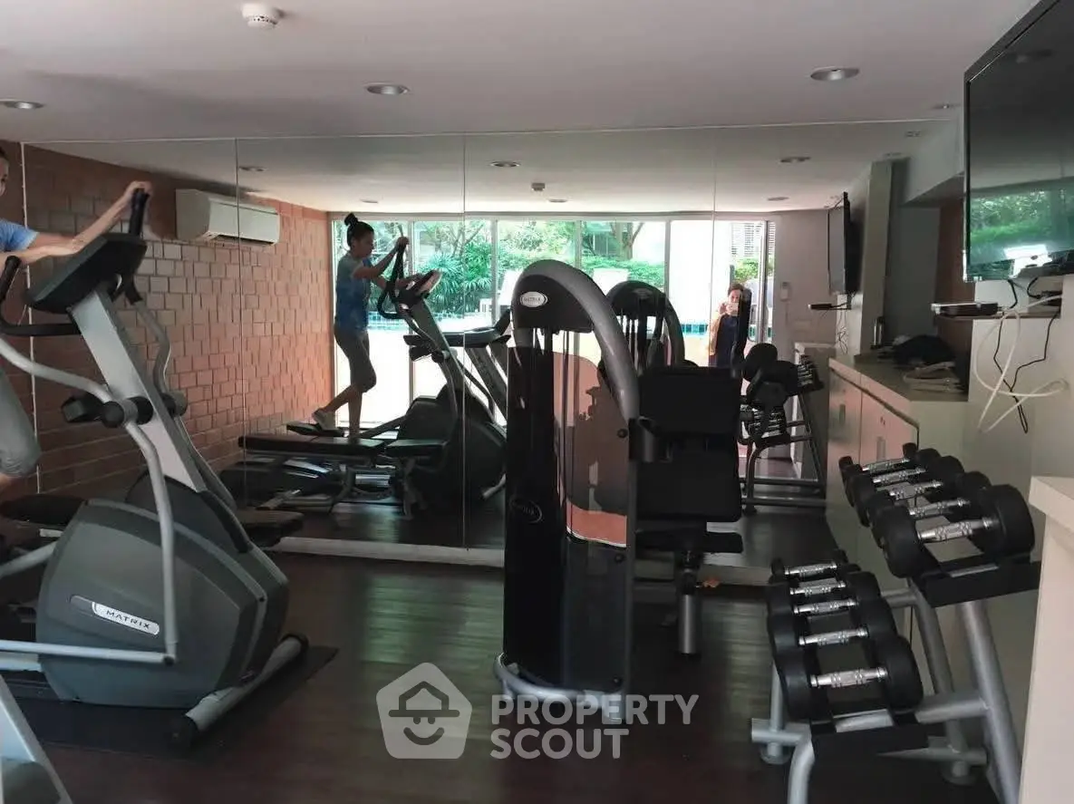 Modern gym with exercise equipment and mirrored walls in a residential building.