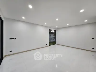 Spacious empty room with modern lighting and large windows, ideal for customization.