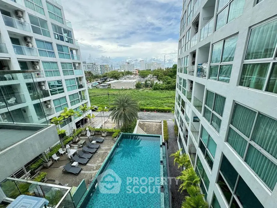 Modern condominium with pool and city view, featuring sleek architecture and lush greenery.