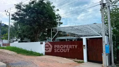 Modern residential property with spacious carport and wooden gate in a serene neighborhood.