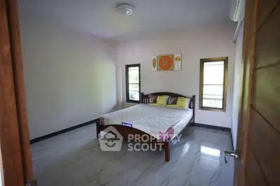 Spacious bedroom with minimalist decor and natural light, perfect for relaxation and comfort.