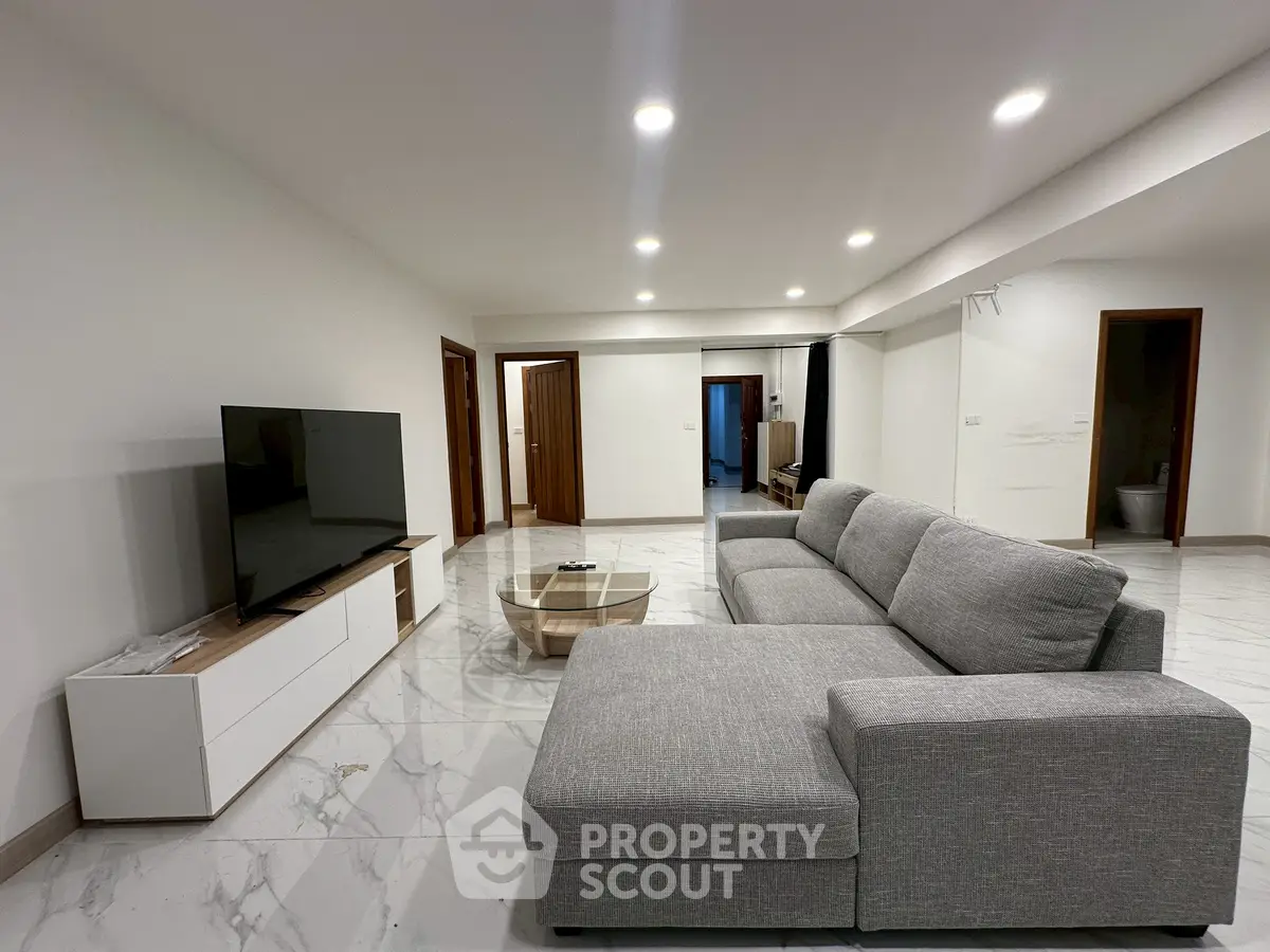 Spacious modern living room with sleek gray sectional sofa and large flat-screen TV.