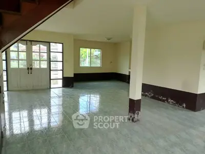 Spacious open-plan living area with large windows and tiled flooring