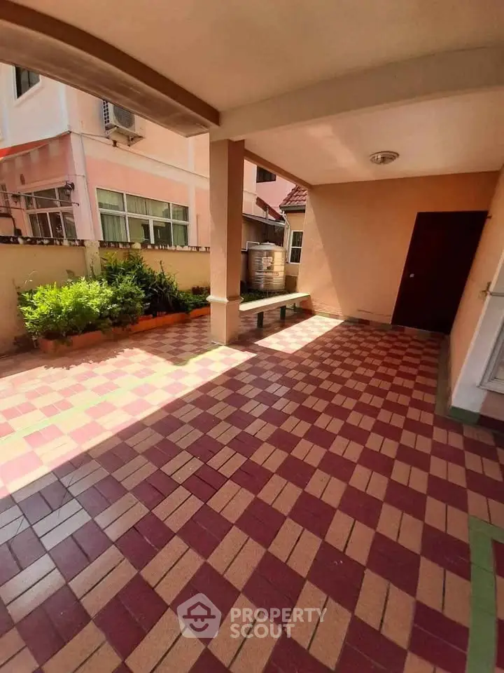 Spacious tiled patio with garden view in a residential property, perfect for outdoor relaxation.