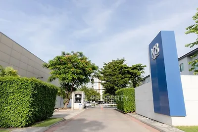 Modern building entrance with lush greenery and clear blue sky