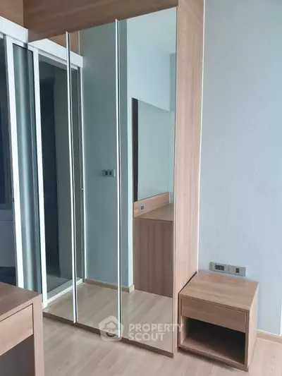 Modern bedroom with sleek mirrored wardrobe and wooden flooring