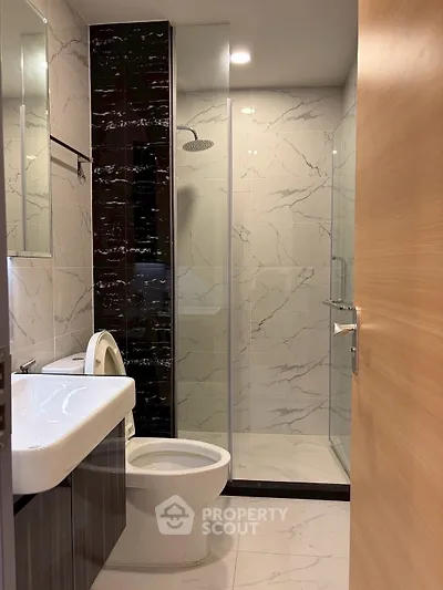 Modern bathroom with sleek marble tiles and glass shower enclosure