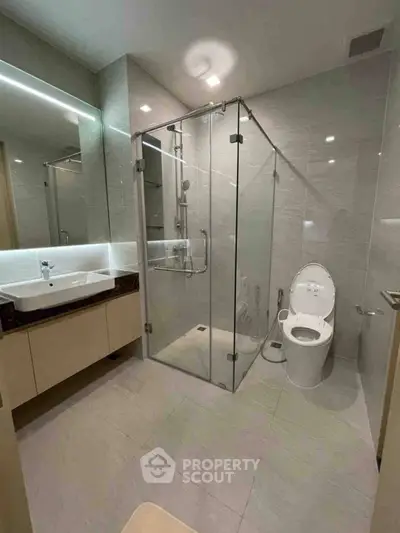 Modern bathroom with glass shower and sleek fixtures in luxury apartment.