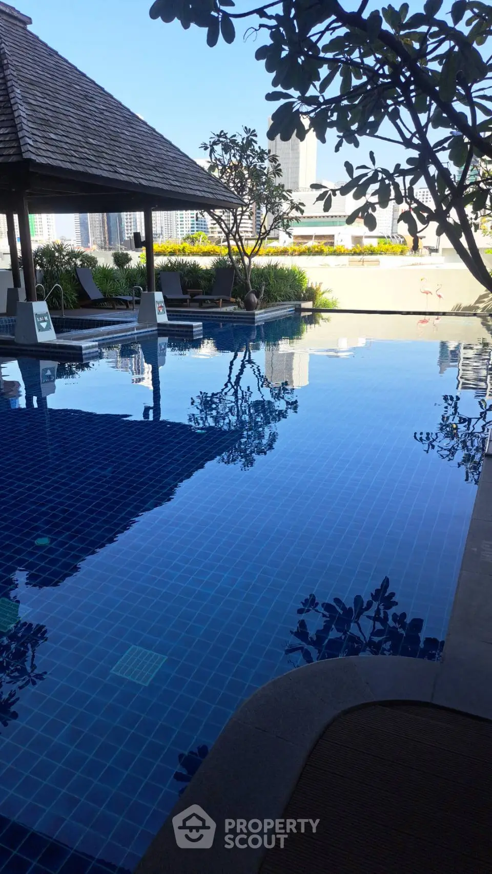 Luxurious rooftop pool with stunning city views and lush greenery, perfect for relaxation and leisure.