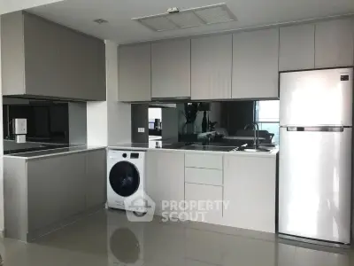 Modern kitchen with sleek cabinetry, washing machine, and stainless steel fridge in a stylish apartment.