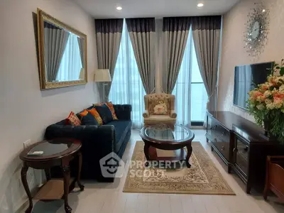 Elegant living room with plush sofa, armchair, and large windows with curtains.