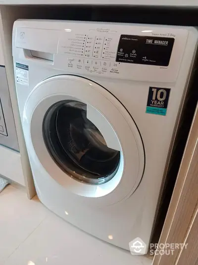 Modern washing machine in sleek laundry area with 10-year warranty sticker