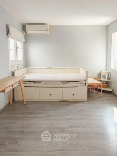 Spacious bedroom with minimalist design and ample natural light, featuring a cozy bed and modern furniture.