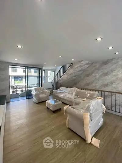 Spacious modern living room with large windows and elegant staircase