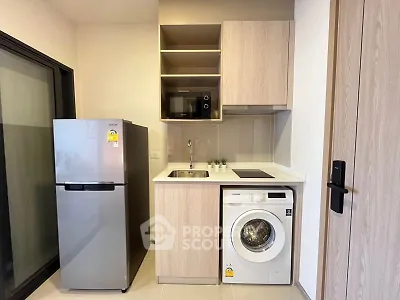 Modern compact kitchen with fridge, washing machine, and microwave in stylish apartment.