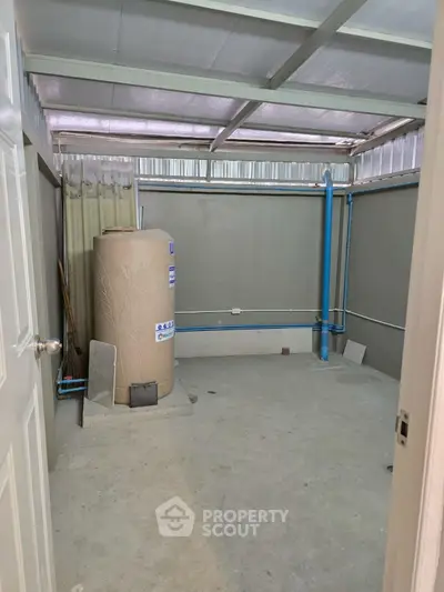 Spacious storage room with water tank and utility pipes