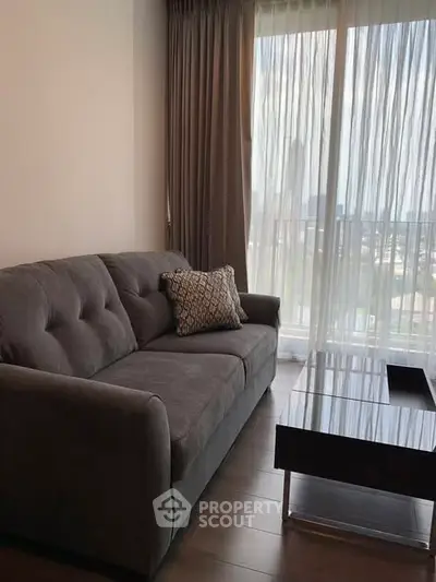 Cozy living room with a plush gray sofa and modern coffee table, featuring a bright window view.