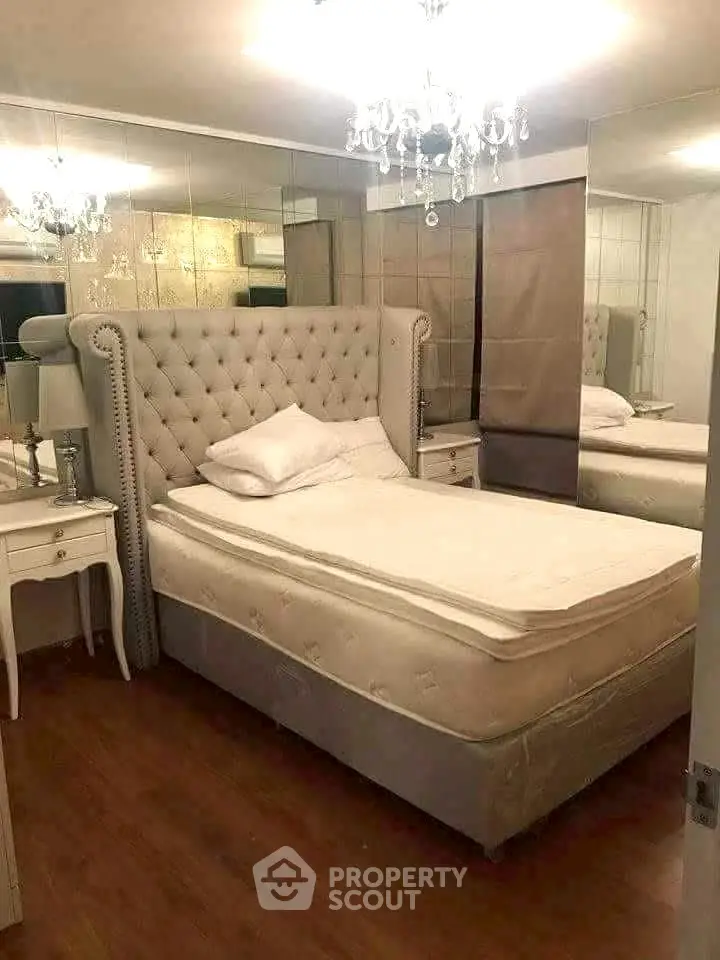 Luxurious bedroom with elegant chandelier and plush bed in modern apartment.