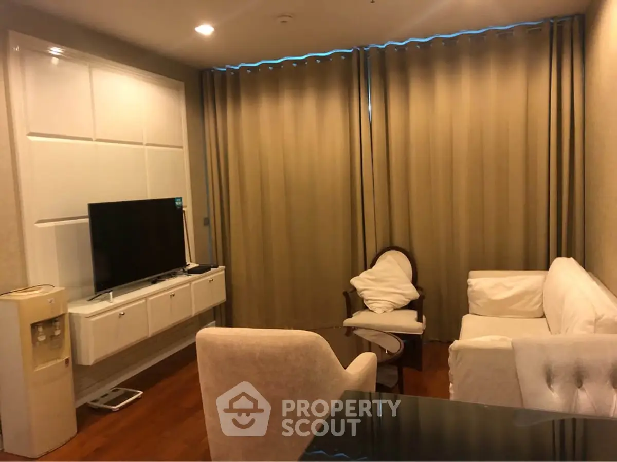 Cozy living room with elegant furniture and large TV, perfect for relaxation.