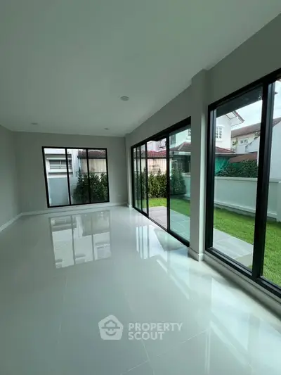 Spacious modern living room with large windows and garden view, perfect for natural light lovers.
