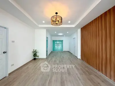 Spacious modern living room with elegant lighting and wood panel accent wall.